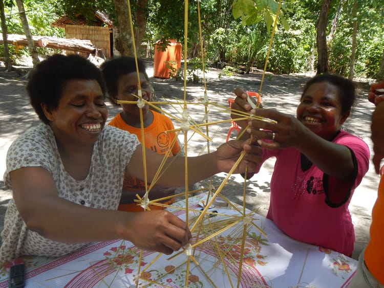 Three Papuan women work together on a workshop activity